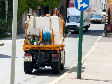 Şehir yolundaki su hortumlu sokak temizleme aracı.