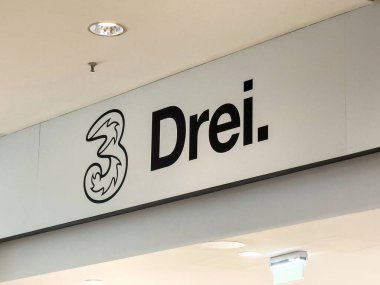 Modern alışveriş merkezinde logolu Drei mobil mağaza tabelası.