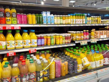 Süpermarket raflarında çeşitli renkli içecek şişeleri var..