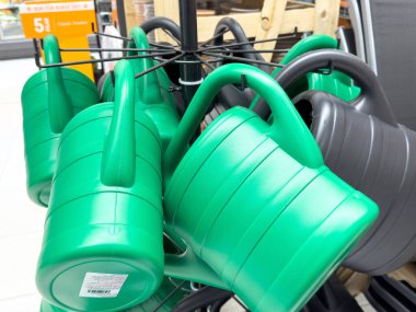 Bahçe malzemeleri deposunun koridorunda sergilenen yeşil ve gri plastik sulama kutuları.