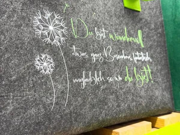 Karahindiba tasarımı, keçeli çanta üzerine Alman ilham verici beyaz ve yeşil alıntısıyla.