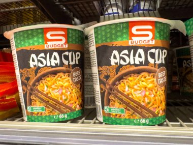 Hazır erişte bardakları yemek çubukları ve sebzelerle dolu raflarda..