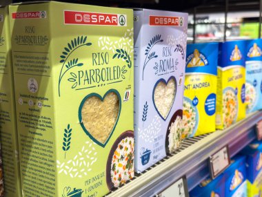 Süpermarketin rafında çeşitli paketlenmiş pirinç kutuları.