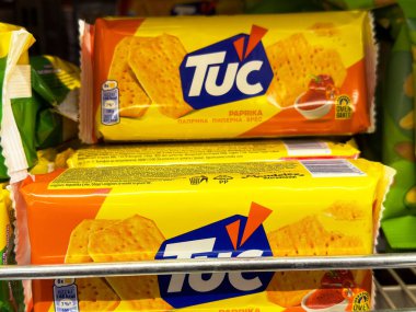 Tuc kırmızı biber krakerleri açık sarı ambalajlı raflarda duruyor..