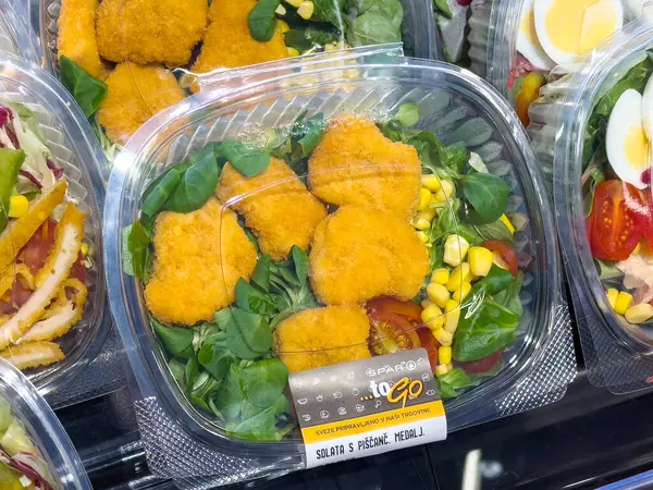 Tavuklu taze salata, mısır ve plastik kabın içinde yeşillikler..