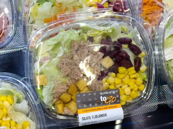 Taze salata, ton balığı, mısır, fasulye ve plastik kabın içinde kızarmış ekmek..