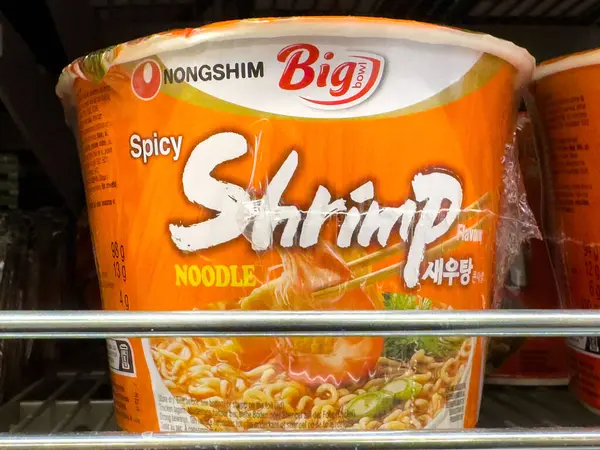 Baharatlı karidesli şehriyeli çorba bardağı ve kalın turuncu ambalajlar..