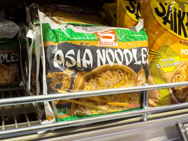 Bütçe asia erişte paketleri renkli ambalajlarla dolu raflarda.