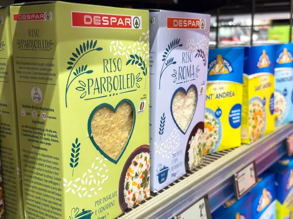 Süpermarketin rafında çeşitli paketlenmiş pirinç kutuları.