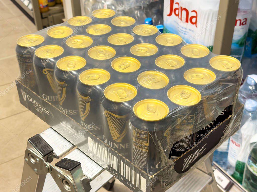 Pack of guinness draught beer cans on store shelf with bottled water in background.