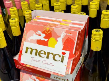 Markette çeşitli çikolatalar ve sarı şarap şişeleri sergileniyor..