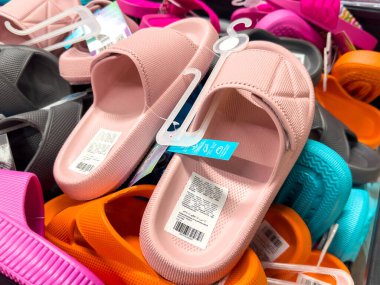 Mağazada çeşitli renkli sandaletler sergileniyor.