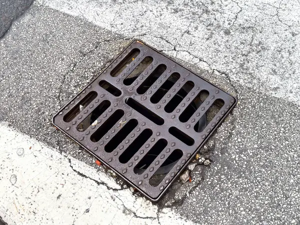 Kırık asfalt yol yüzeyinde metal akıntısı olan şehir kaldırımı..