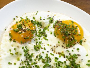 Beyaz tabakta soğan ve biber garnitürlü güneşli yumurta yakın plan..