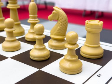 Damalı bir tahtada sarı satranç taşlarının yakın plan çekimi.