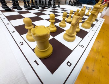 Ahşap bir masanın üzerinde sarı parçalar olan satranç tahtasının yakın görüntüsü..