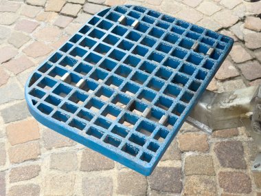 Çakıl taşı yüzeyinde endüstriyel kullanım için mavi metal ızgara.
