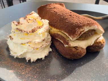 Klasik tiramisu tatlısı, gri tabakta krem şanti..