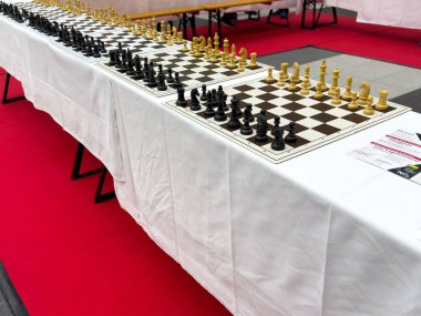 Satranç turnuvası hazırlığı. Masalarda birden fazla tahta var..