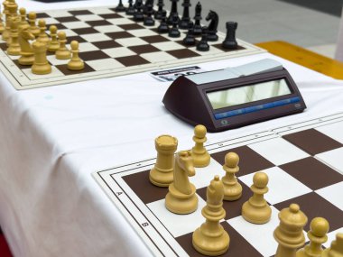 Satranç turnuvası, dijital saat ve beyaz masa örtüsü üzerinde satranç taşları..
