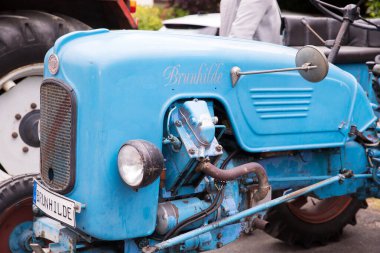 Açık hava etkinliğinde plakalı klasik mavi traktör.