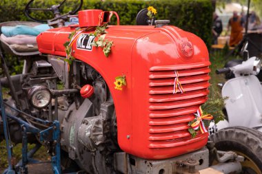 Açık hava gösterisi sırasında çiçeklerle süslenmiş klasik kırmızı traktör..