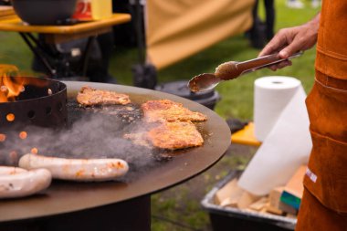 Erkek, yaz günü dışarıda et ve sosis pişiriyor..