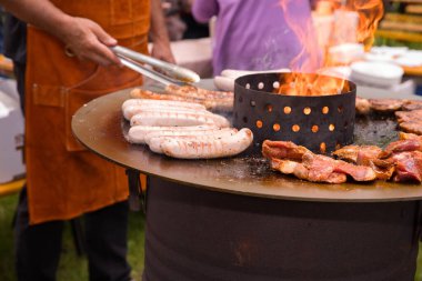 Kızarmış sosis ve yanan ateş çukurunda et ile dışarıda barbekü..