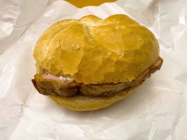 Beyaz kağıtta çıtır çörekli leziz bir domuz sandviçi..