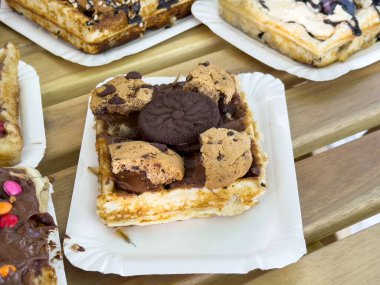 Çikolata parçacıklı waffle ve kâğıt tabakta oreo sosu..