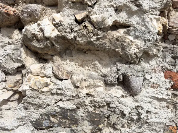 Yıpranmış yüzeyli taş duvarın yakın görüntüsü.