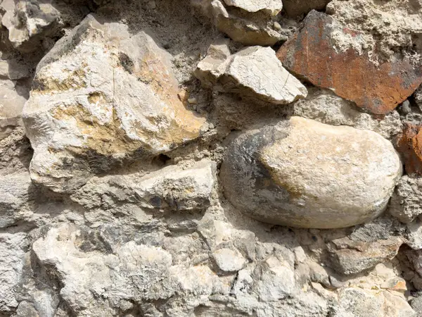 Değişik dokuları ve doğal renkleriyle yıpranmış taş duvarlara yakın çekim.