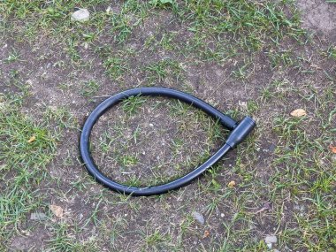 Açık havada çimen yüzeyine siyah bisiklet kilidi.