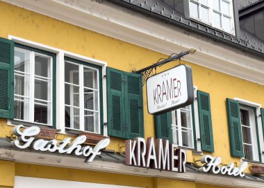 Yeşil kepenkleri ve klasik tabelası olan büyüleyici sarı bir otel dış görünüşü var..