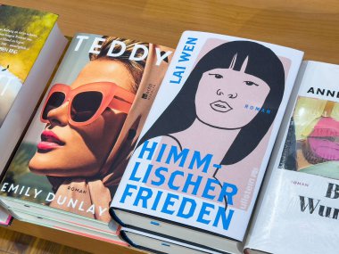 Çeşitli kitap kapakları kadın yazarları vurgulayan ahşap masa üzerinde sergilenir.