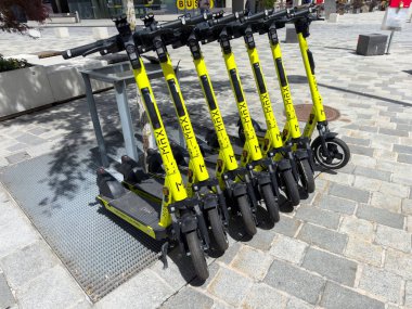 Şehir kaldırımına park edilmiş sarı elektrikli scooterlar..