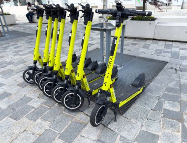 Sarı elektrikli scooterlar şehir ulaşımı için şehir caddesinde sıraya girdiler..