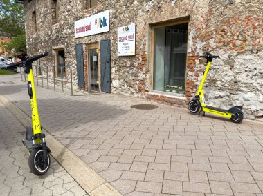 Elektrikli scooter 'lar, güneşli bir günde taşra binasının yanına park edilmiş..