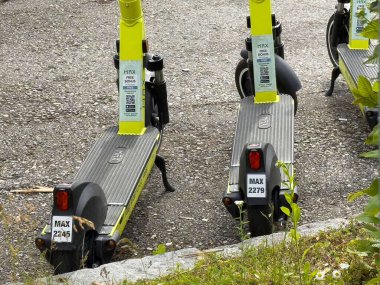 Yeşillik ve şehir ortamında park edilmiş elektrikli scooterlar..