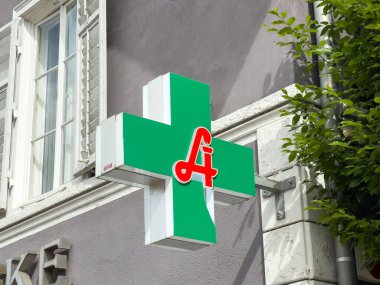 Dış binanın üzerinde kırmızı sembollü yeşil eczane işareti var..