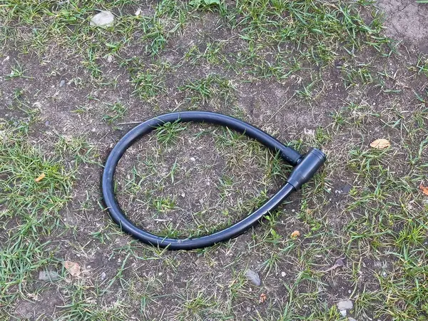 Açık havada çimen yüzeyine siyah bisiklet kilidi.