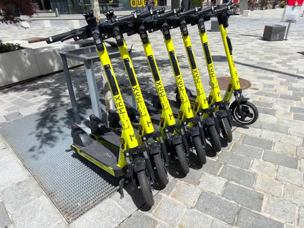 Şehir kaldırımına park edilmiş sarı elektrikli scooterlar..