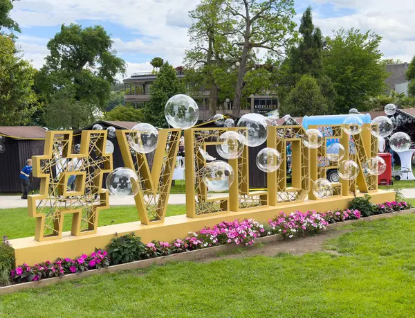 Yeşillik bahçe ortamında hashtag ve şeffaf küreler ile büyük açık hava görüntüsü.