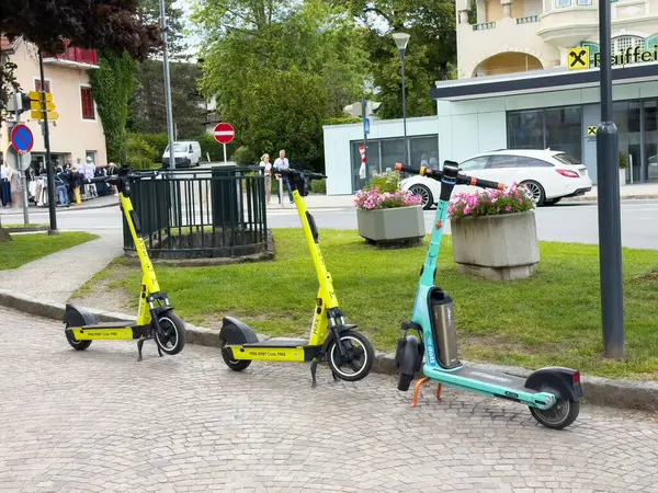 Şehir meydanının yakınındaki kaldırım taşı sokağına park etmiş renkli elektrikli scooterlar..