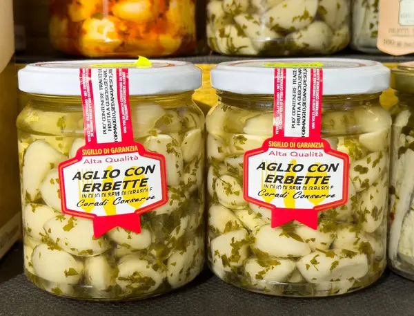 İtalyan salamura sarımsak kavanozları ve raflarda otlar..