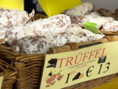 Hasır sepette, pazarda fiyat etiketli çeşitli salam görüntüsü..