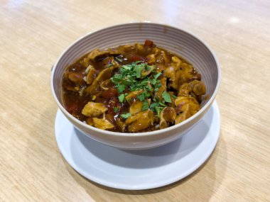 Lezzetli körili tavuk kasesi ahşap masada taze kişniş ile süslenmiş..