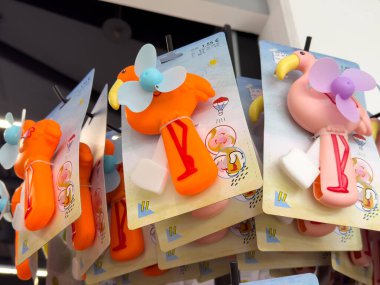 Renkli flamingo ve turuncu pervaneler vitrinde.