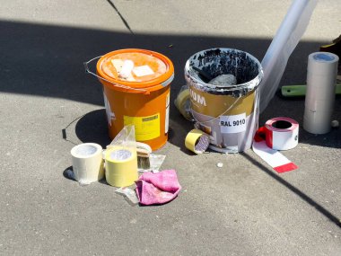 Asfalt yüzeyinde kovalarla, bantlarla ve temizlik bezleriyle çeşitli boya malzemeleri..