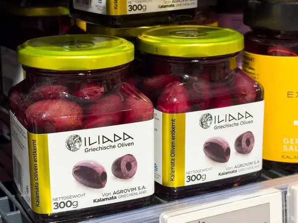 Iliada Yunan zeytinleri cam kavanozlarda ve market raflarında yeşil kapaklı..